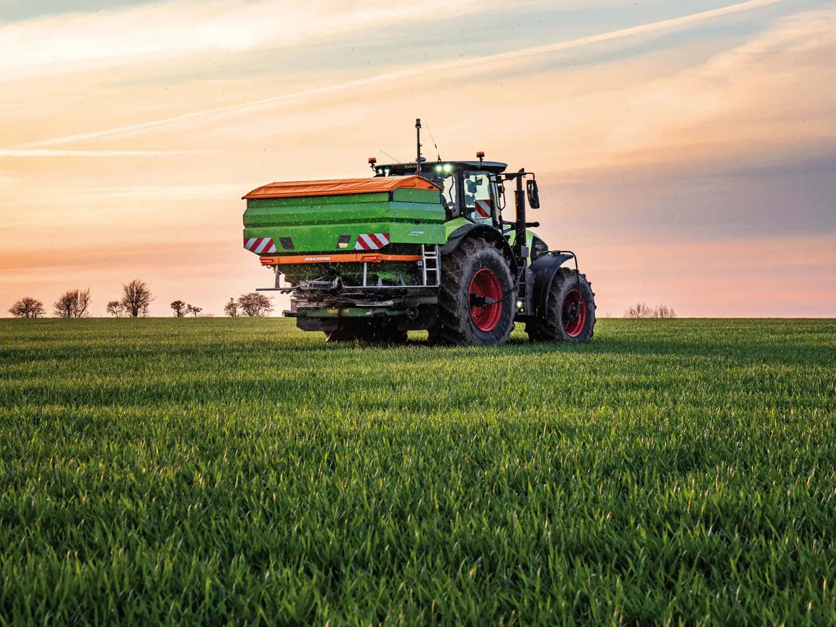 Amazone abonadora centrífuga en campo de cereal al atardecer
